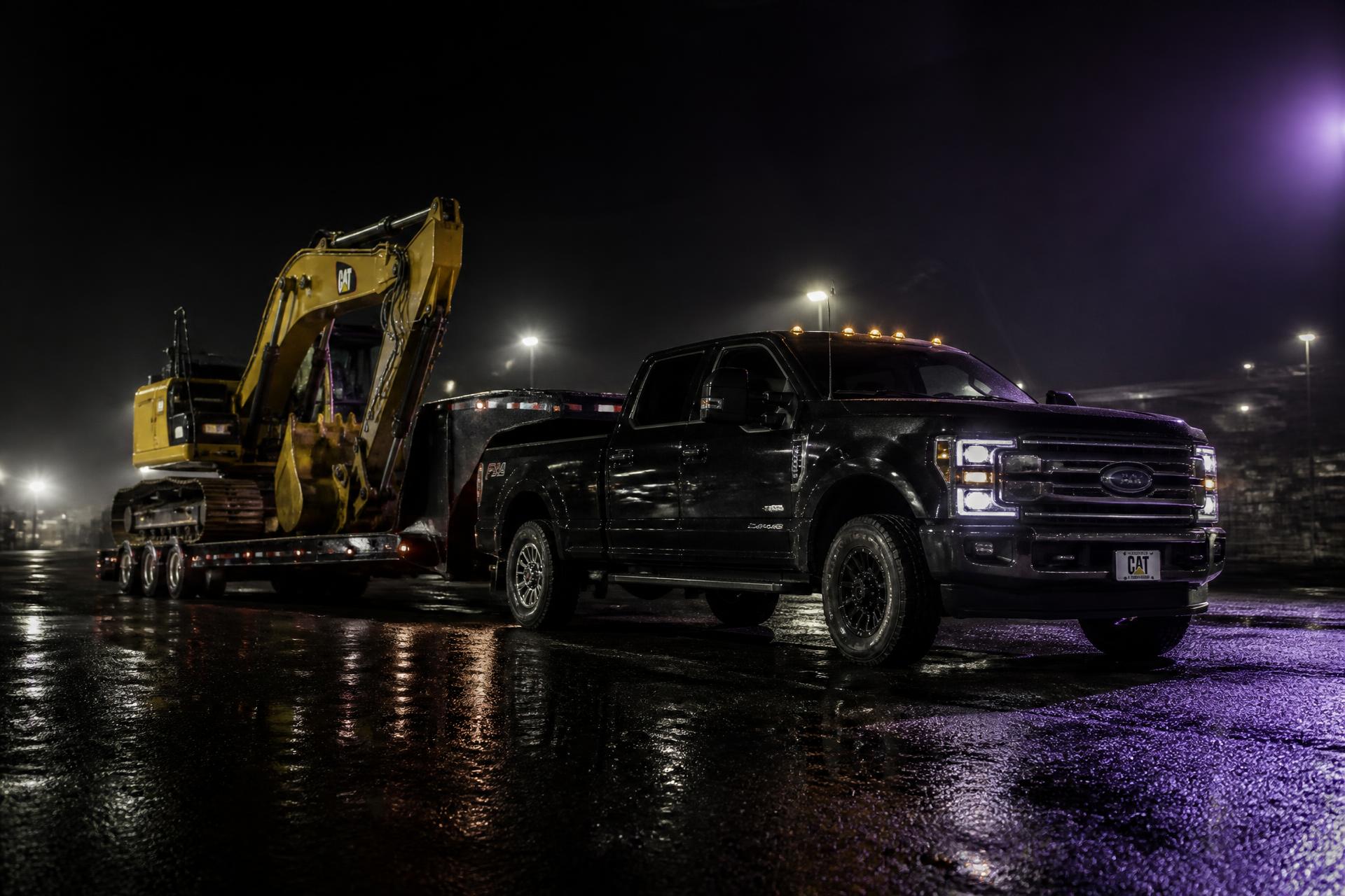 Camion lourd avec remorque plateforme transportant une excavatrice la nuit