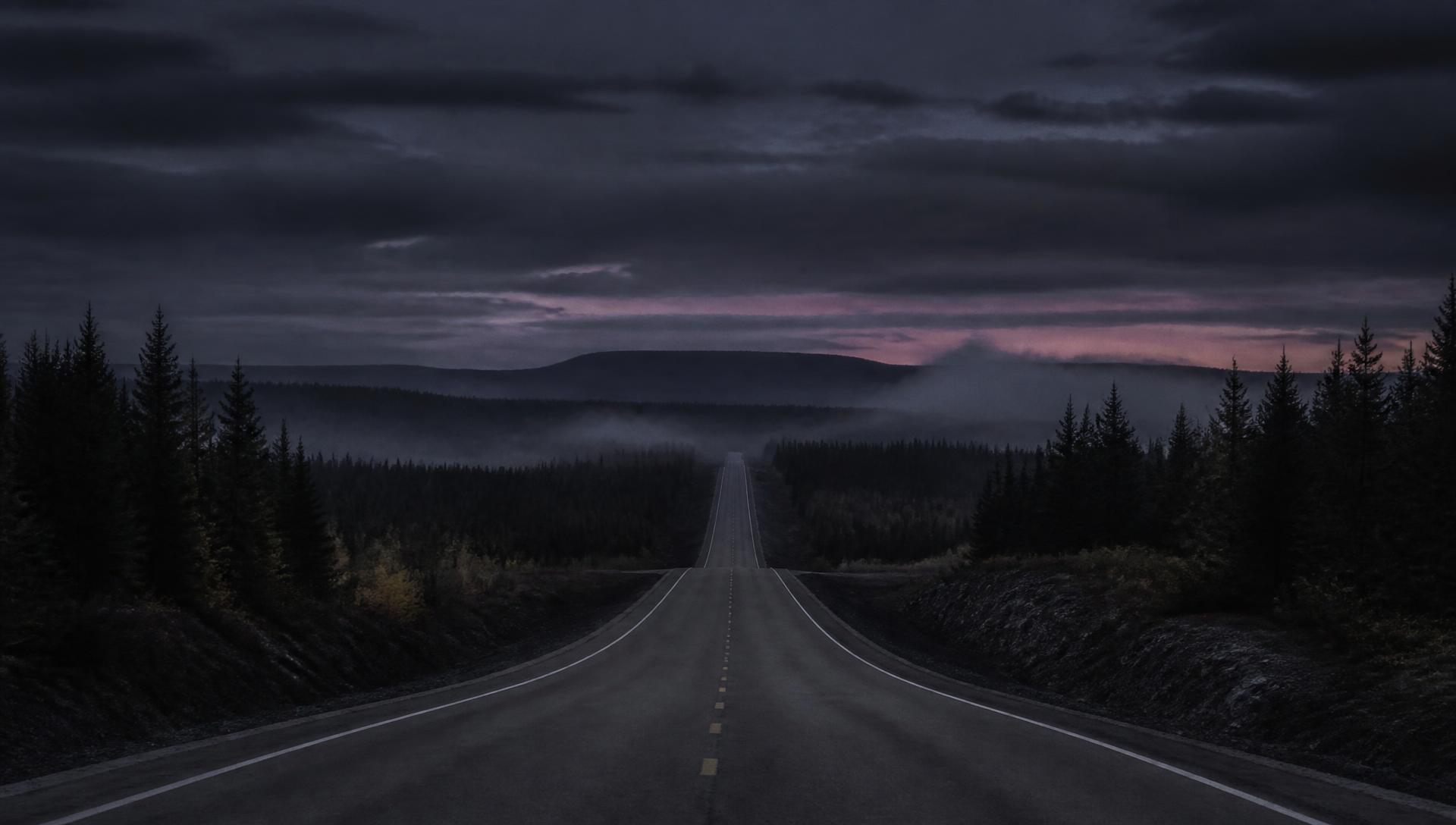 Route isolée traversant la forêt boréale au crépuscule